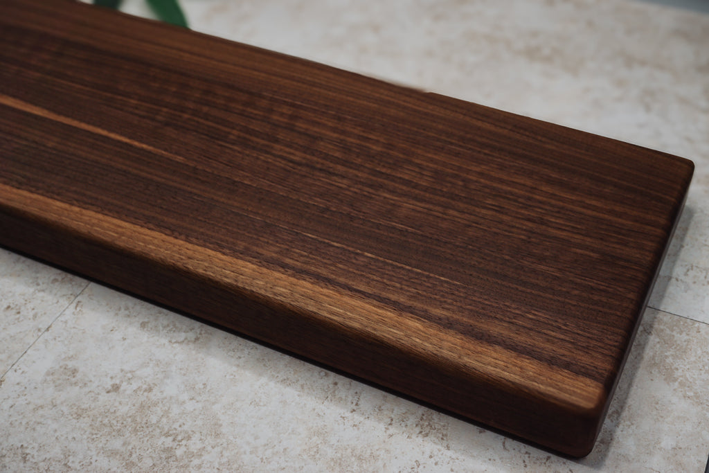 Close angled view of the thick walnut serving board showing its rich grain and squared edge