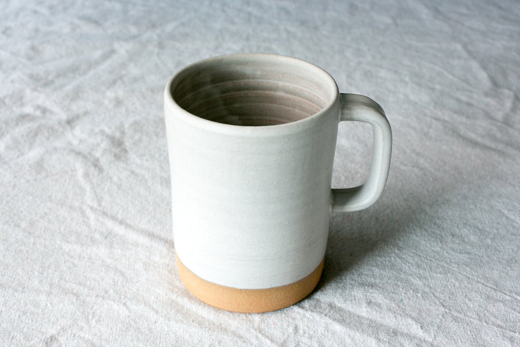 Hand-Thrown Stoneware Cappuccino Mug shown in warm window light on an adobe toned shelf at home