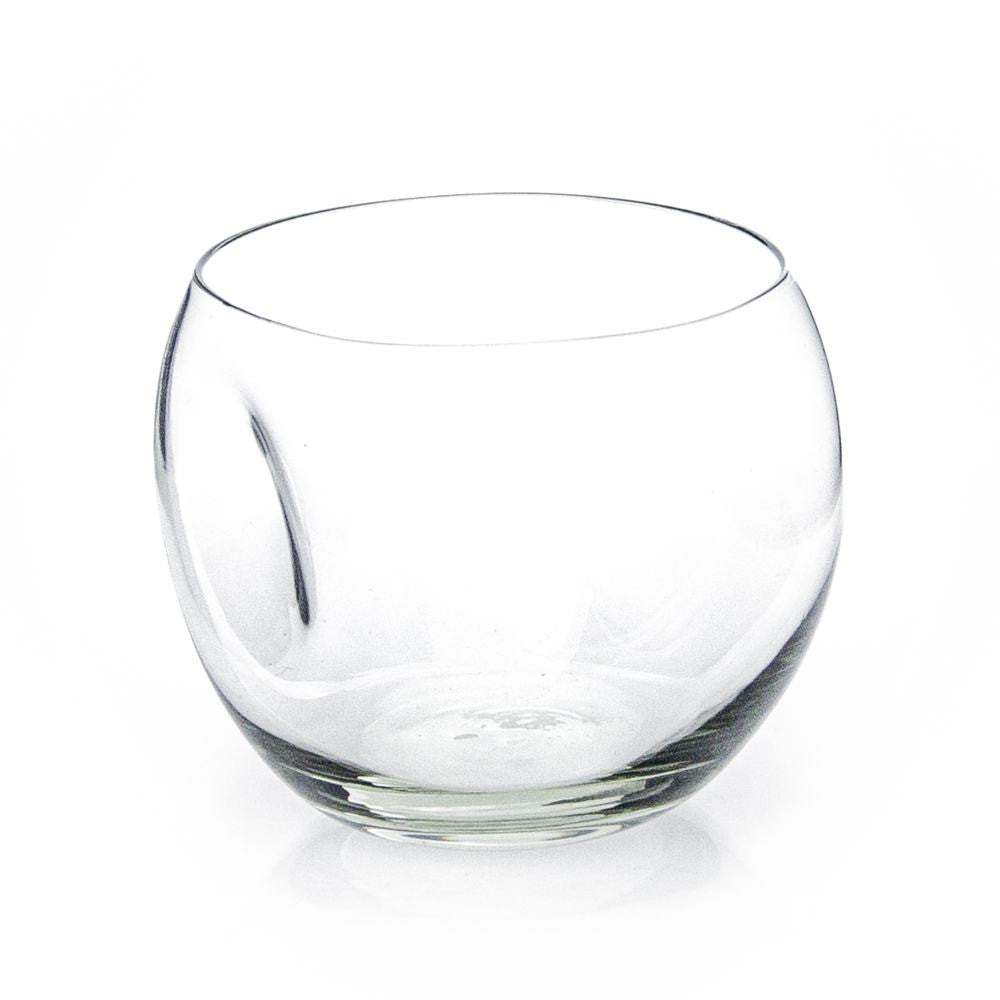Empty round handblown recycled glass whiskey tumbler with a pressed dent in its side on white