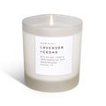 Frosted glass lavender and cedar soy candle with a white label, lit against a plain white background