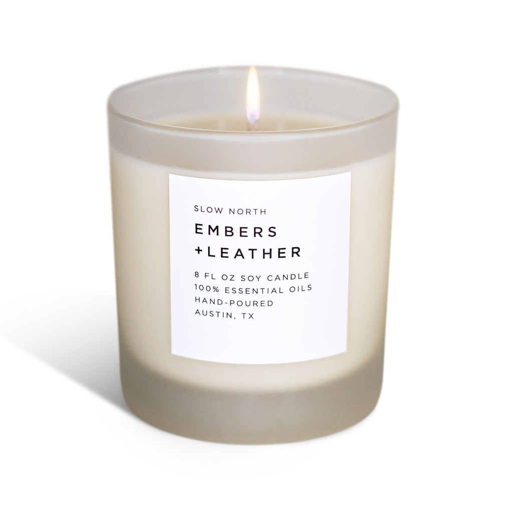 Frosted glass vetiver and cedar soy candle lit against a plain white background with a soft shadow