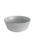 Carved matte white ceramic serving bowl with vertical lines around the outside on a black background