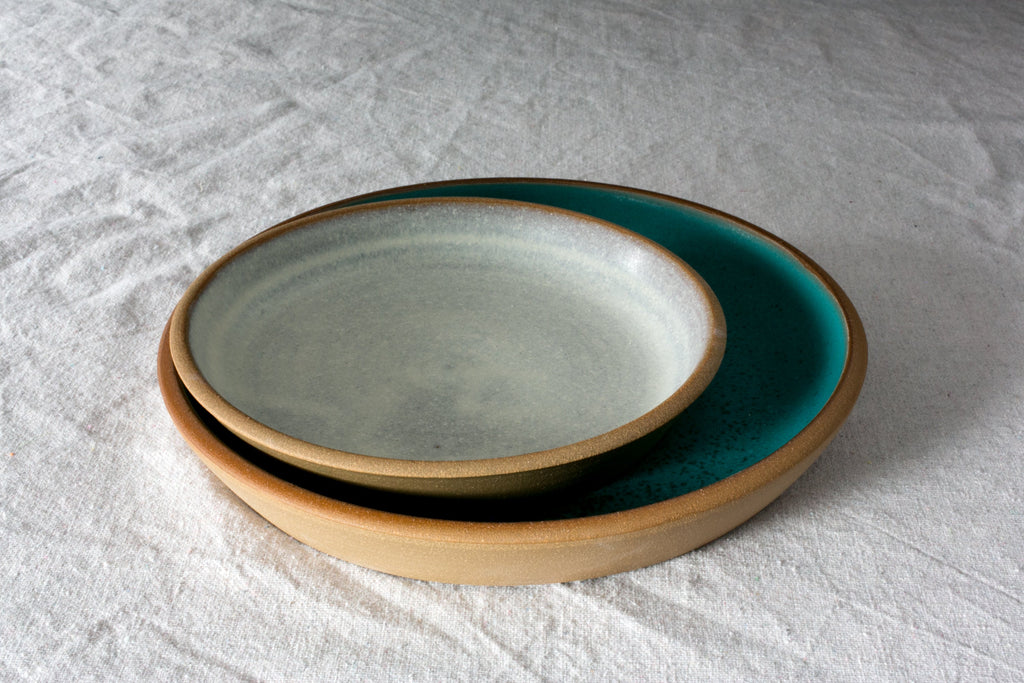 Small Fat Rim stoneware lunch plate in pale oat nested inside a larger turquoise plate on white linen