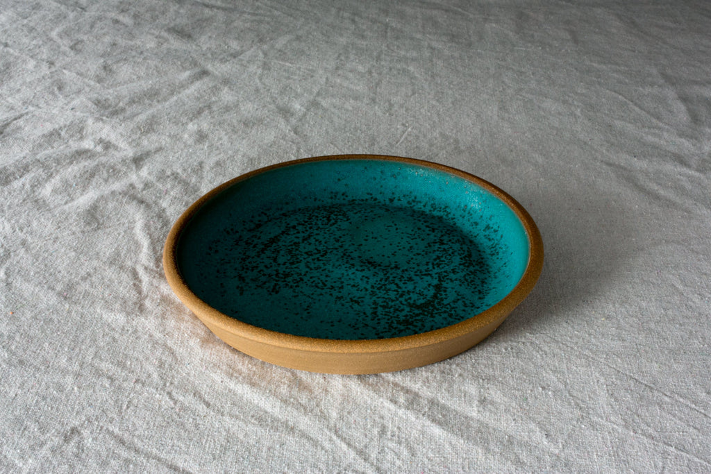 Fat Rim stoneware lunch plate in a speckled turquoise glaze with a dark center, set on white linen