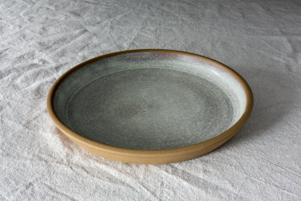 Fat Rim stoneware dinner plate in a pale speckled oat glaze with a raw clay rim on rumpled white linen