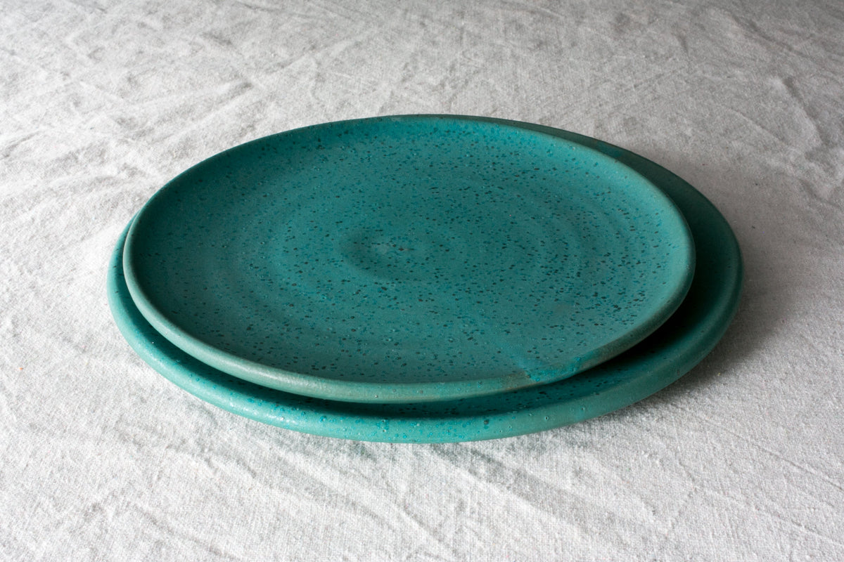 Two Horizon stoneware dinner plates in a speckled turquoise glaze stacked on a white linen cloth
