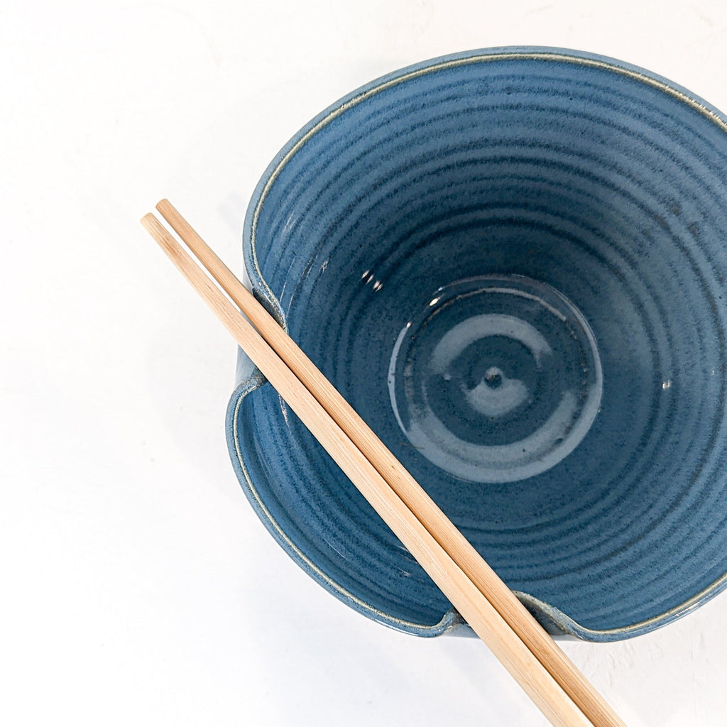 Sky blue glazed stoneware ramen bowl seen from above with chopsticks tucked into the folded lip