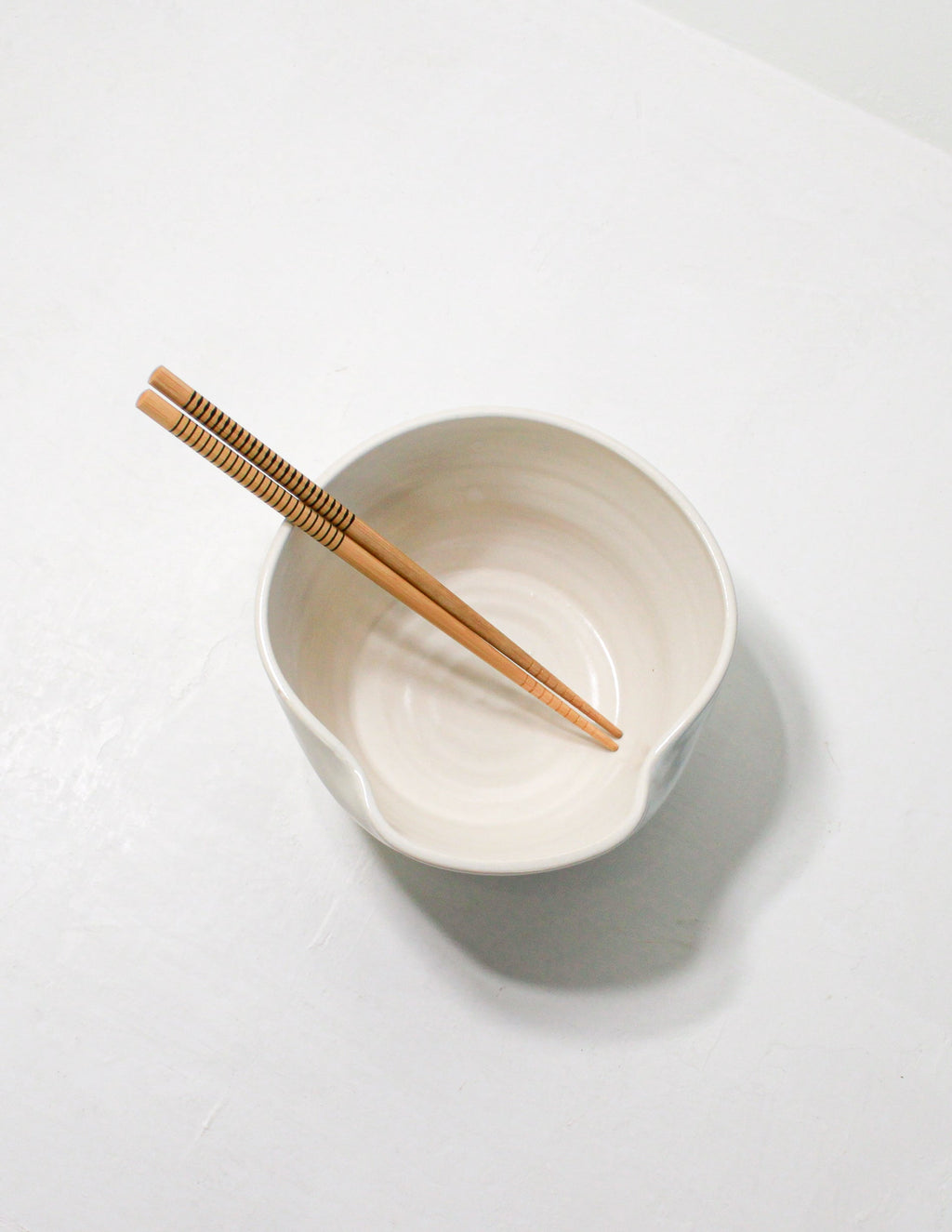 White glazed hand-thrown stoneware ramen bowl from above with chopsticks resting in the pinched lip