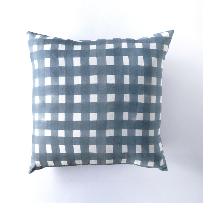 Square linen throw pillow in slate blue with a painted white cross-hatch check pattern, front view on white