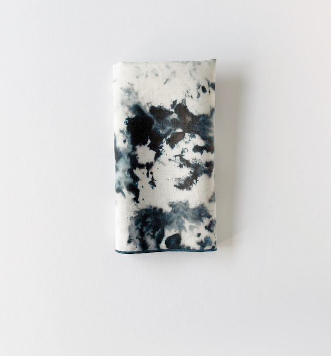 Grey marble print linen napkin folded into a neat rectangle with a dark grey edge on white