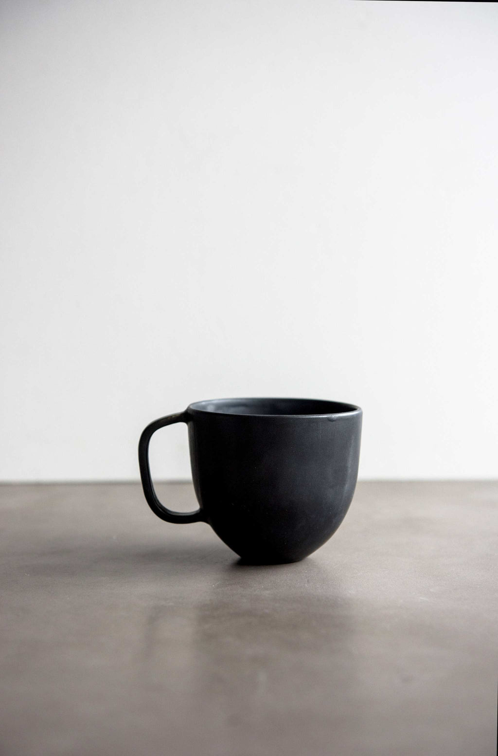 Matte Black Stoneware Mug shown from a second angle against a pale neutral backdrop