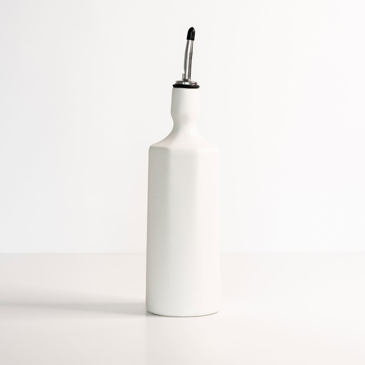 Porcelain Olive Oil Dispenser photographed on a bone white surface in soft natural light