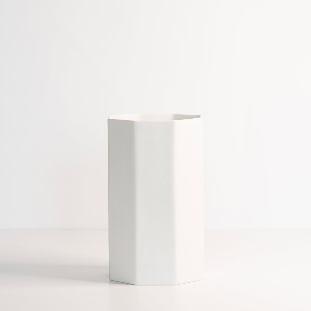 Empty tall octagonal porcelain vase in Silk White on a white surface, showing its clean flat facets