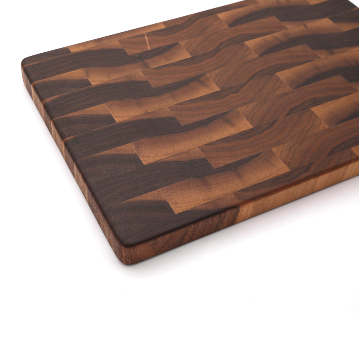 Close view of an end grain walnut cutting board corner showing the rounded edge and brick pattern