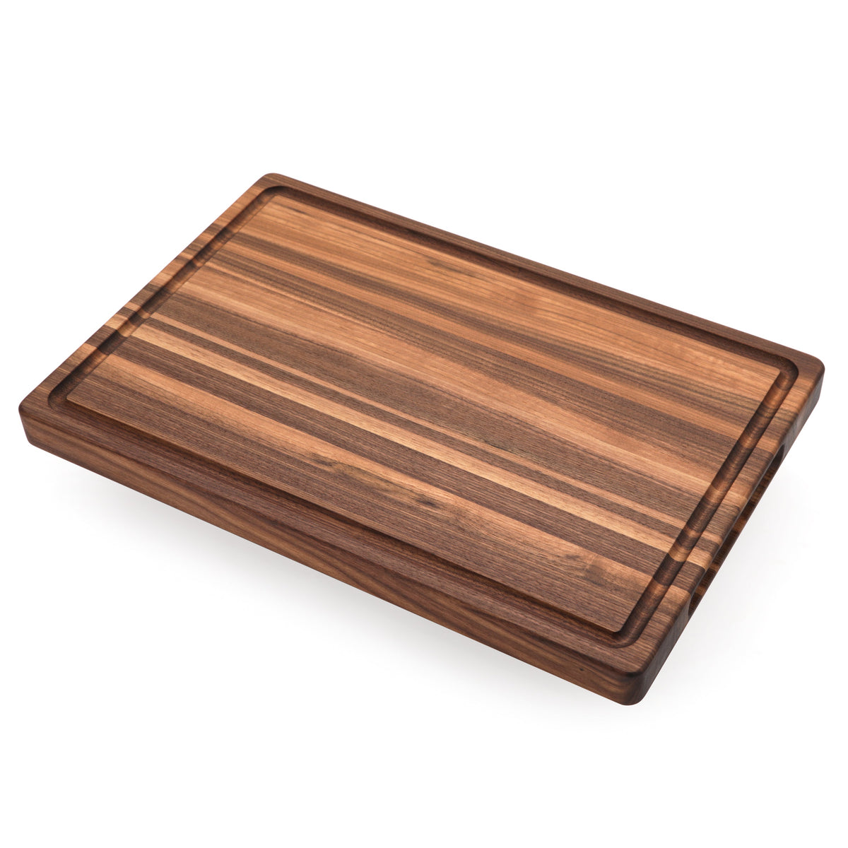 Edge grain walnut cutting board with a juice groove, 18 x 12 in, lying at an angle on white