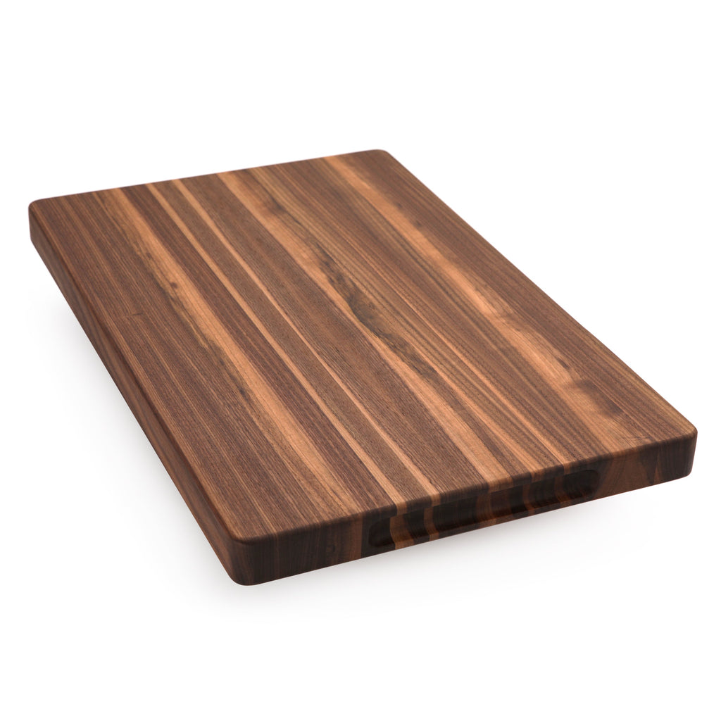Edge grain walnut cutting board, 18 x 12 in, plain face lying at an angle on white with warm striped grain