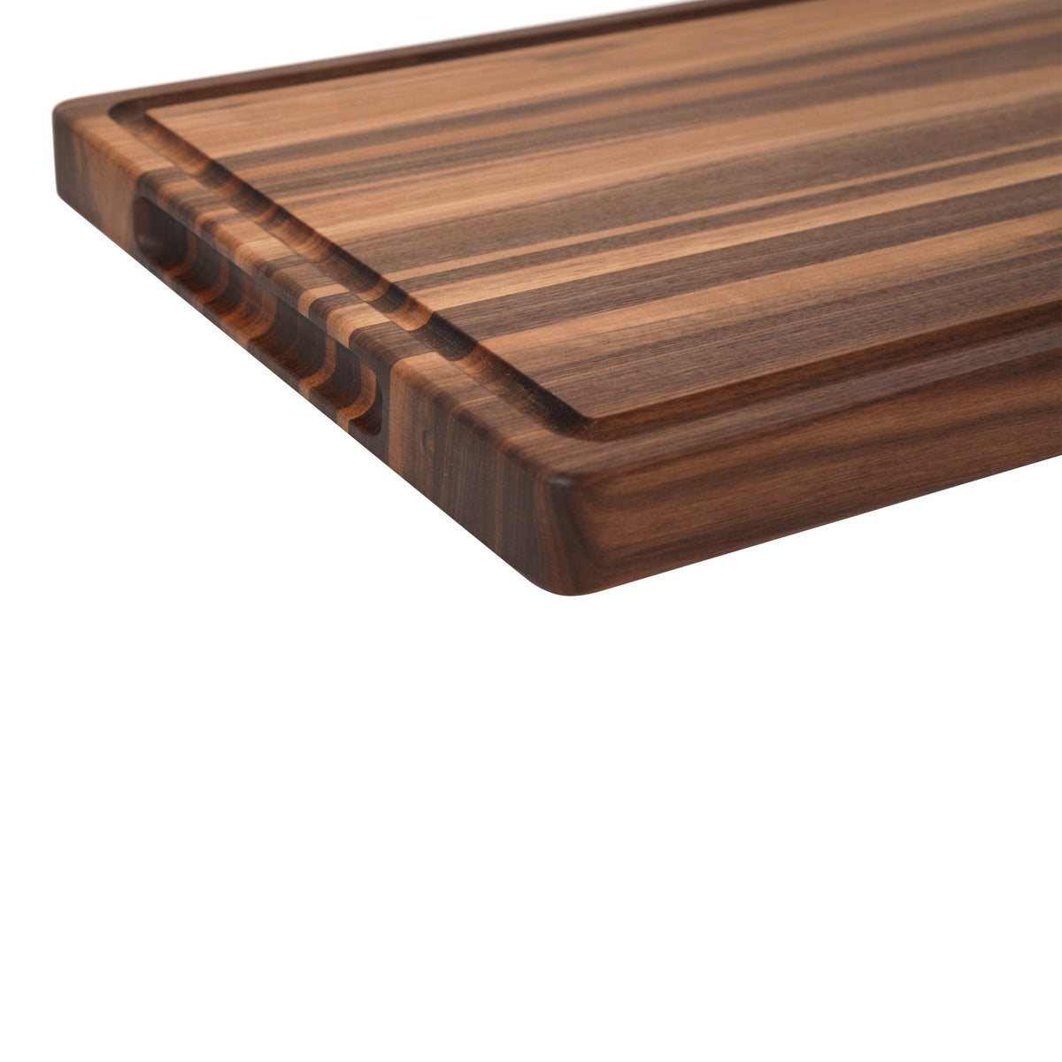 Corner close-up of an edge grain walnut cutting board with a juice groove, showing the striped edge