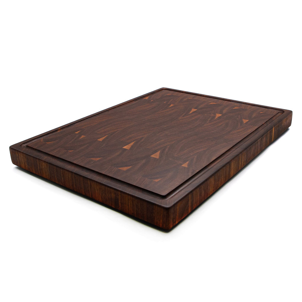 End grain walnut cutting board with a juice groove, 20 x 15 in, lying at an angle on white