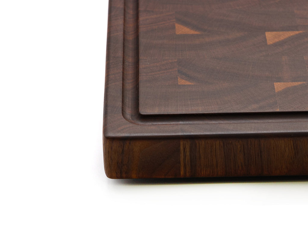 Close view of the thick edge of an end grain walnut cutting board with the groove along the top