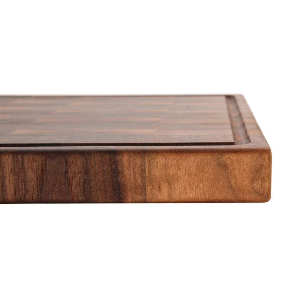 Close view of the striped side of a 2 inch thick walnut end grain butcher block on white