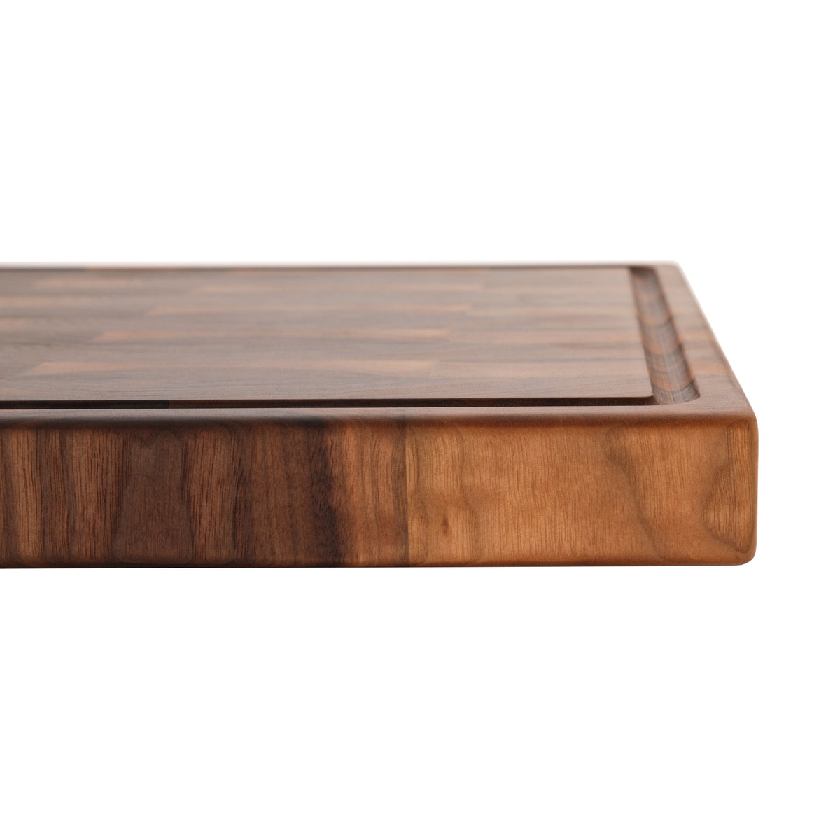 Close view of the striped side of a 2 inch thick walnut end grain butcher block on white