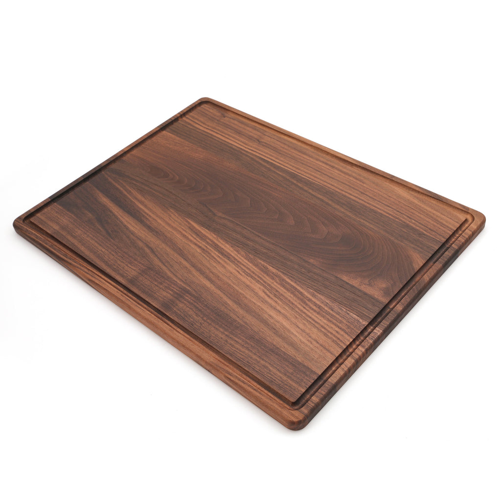 Extra large walnut cutting board with a juice groove, 24 x 18 in, angled view on white showing the thin edge