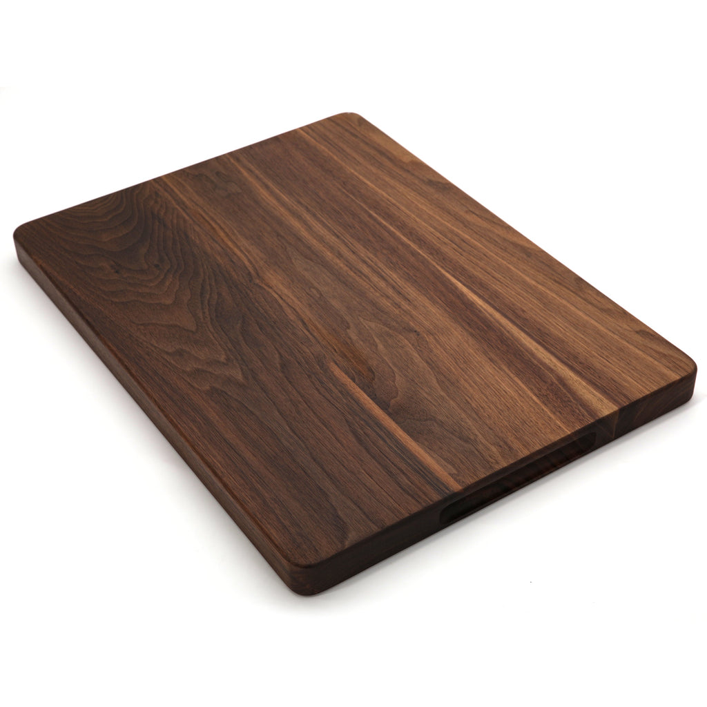 Thick walnut cutting board, 20 x 15 in, lying at an angle on white with mixed dark and light grain