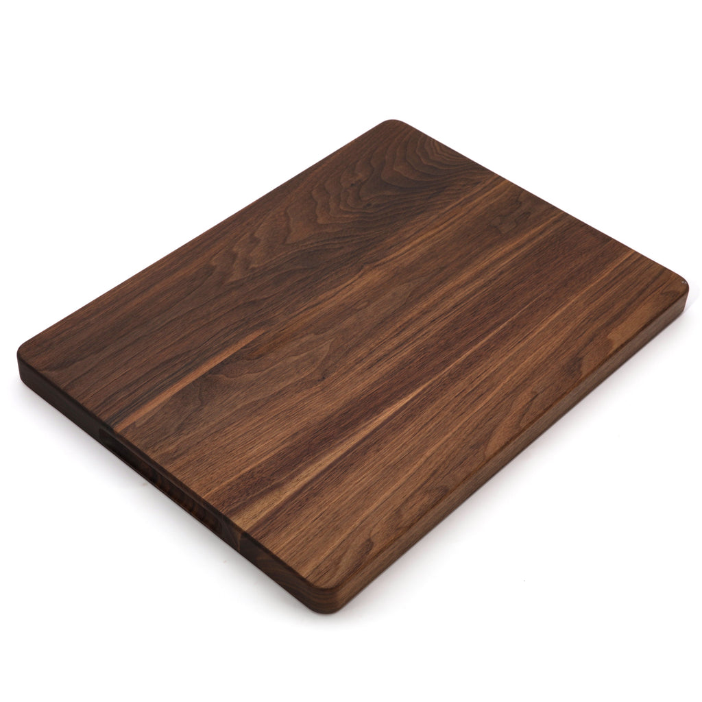 Thick walnut cutting board, 20 x 15 in, angled view of the plain face with warm grain on white