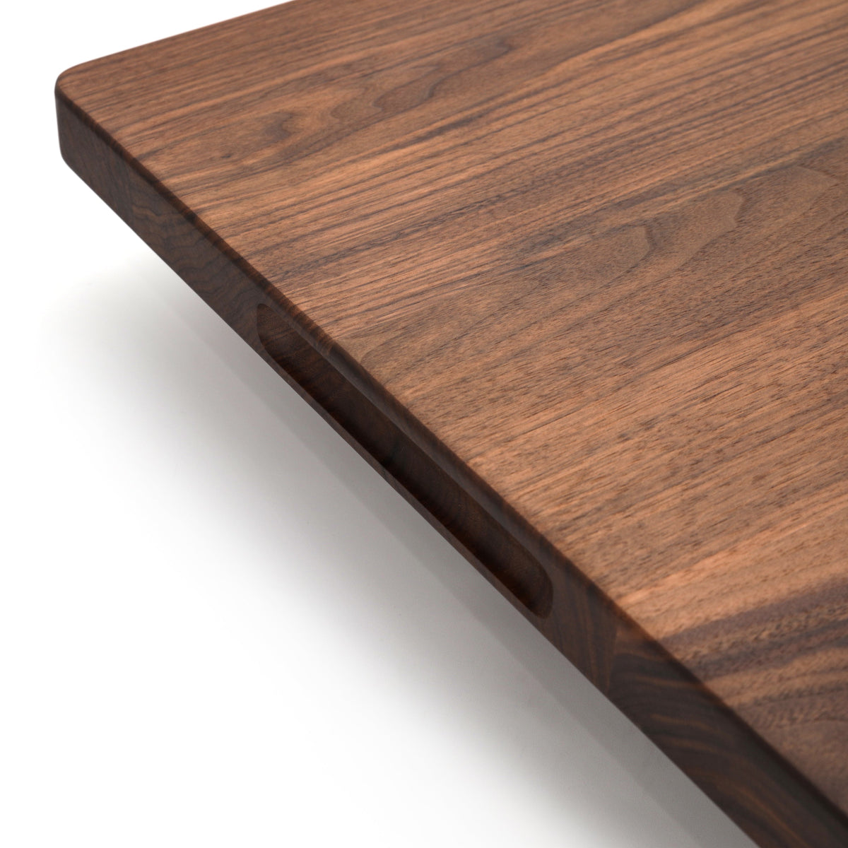 Corner close-up of an extra large thick walnut cutting board showing the squared edge and pocket handle