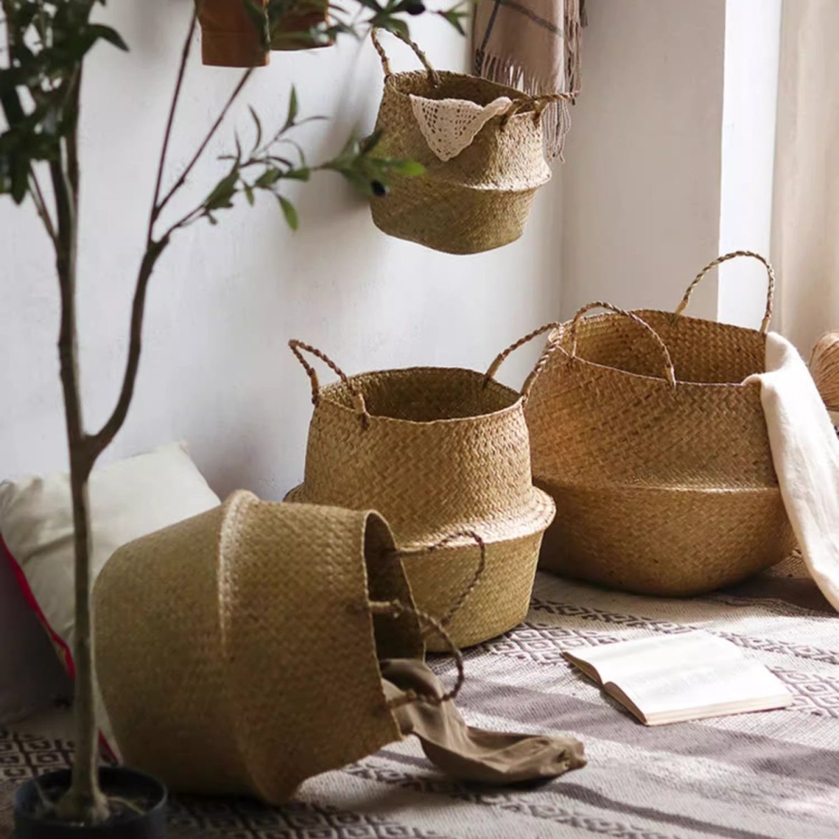 Seagrass belly baskets with handles in three sizes on a window seat, one hanging and one tipped over