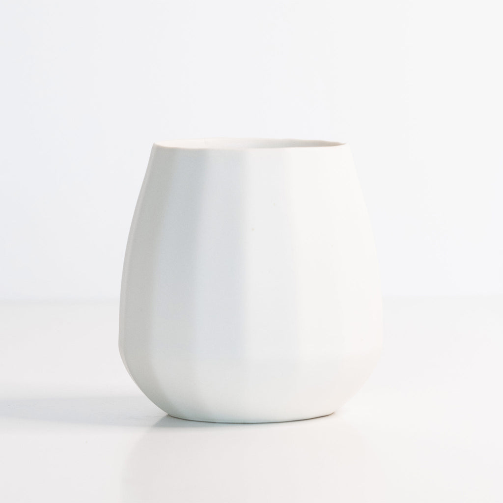 Silk White porcelain stemless wine glass with a rounded faceted body on a bright white surface