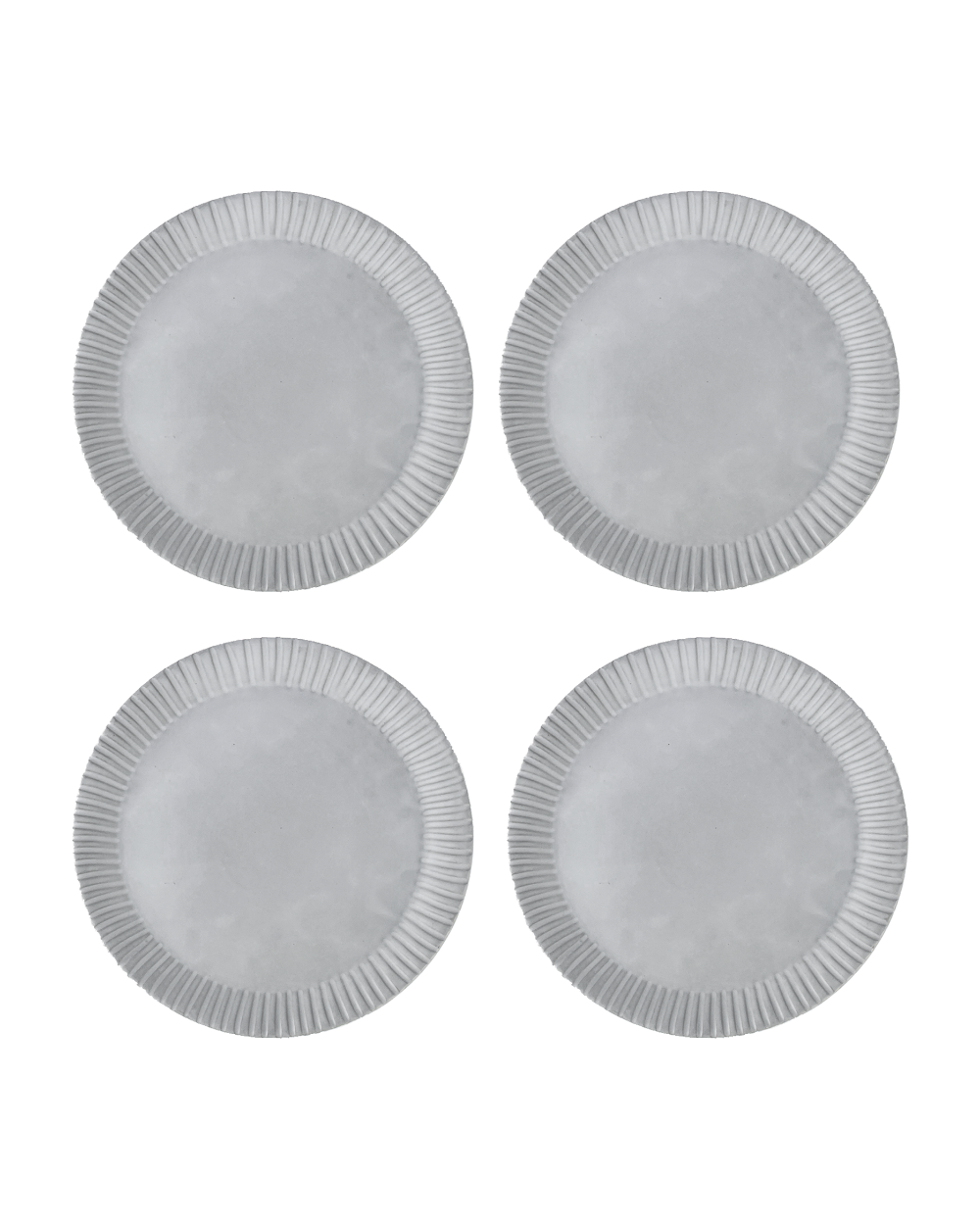 Four matte white ceramic dinner plates with hand-carved line rims, shown from above on a black ground