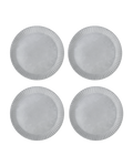 Four matte white ceramic dinner plates with hand-carved line rims, shown from above on a black ground