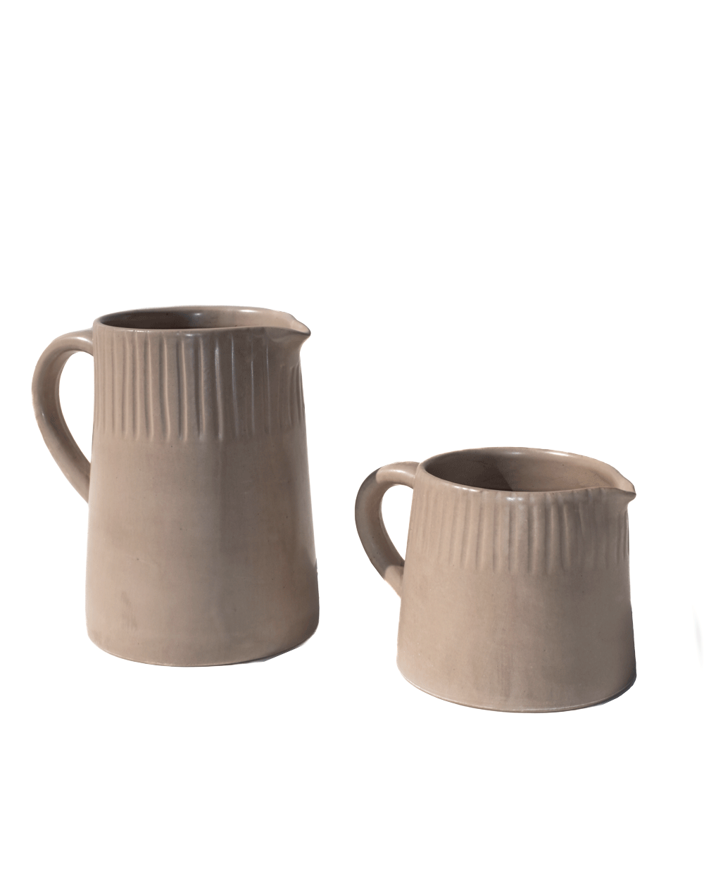 Two carved clay-toned ceramic pitchers in large and small sizes on a deep green background