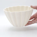 Fluted white porcelain candle holder held in one hand to show its scalloped rim and true size