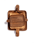 Three nested walnut serving trays with handles at each end, stacked from large to small on green