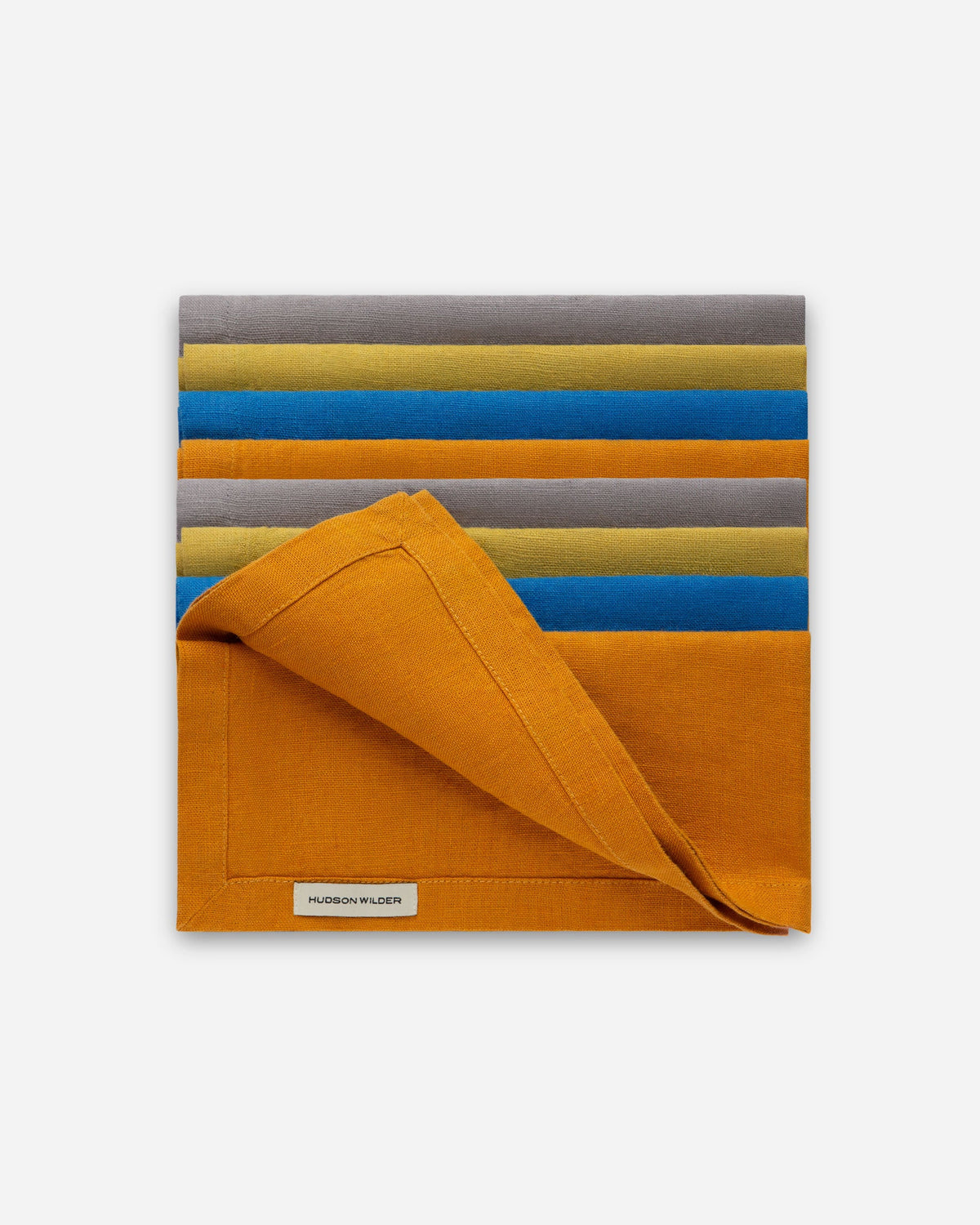 Stack of folded linen napkins in a striped mix of colors with a turmeric orange napkin folded back on top