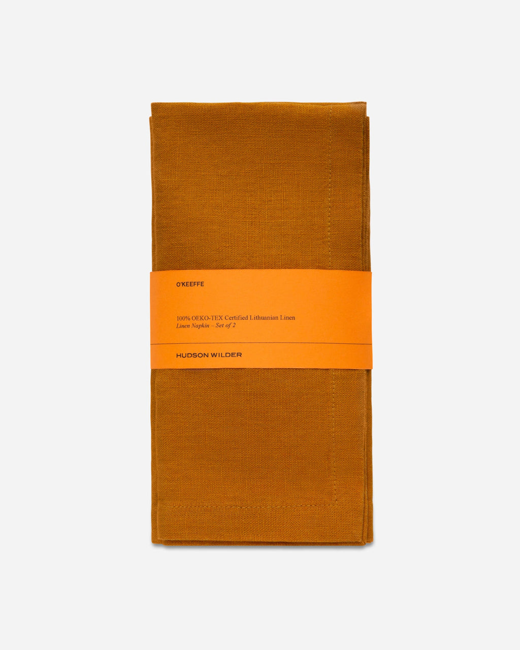 Folded turmeric orange linen napkin set wrapped with a printed paper band on a pale gray background