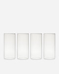 Four tall clear handblown drinking glasses lined up in a row on a pale gray background