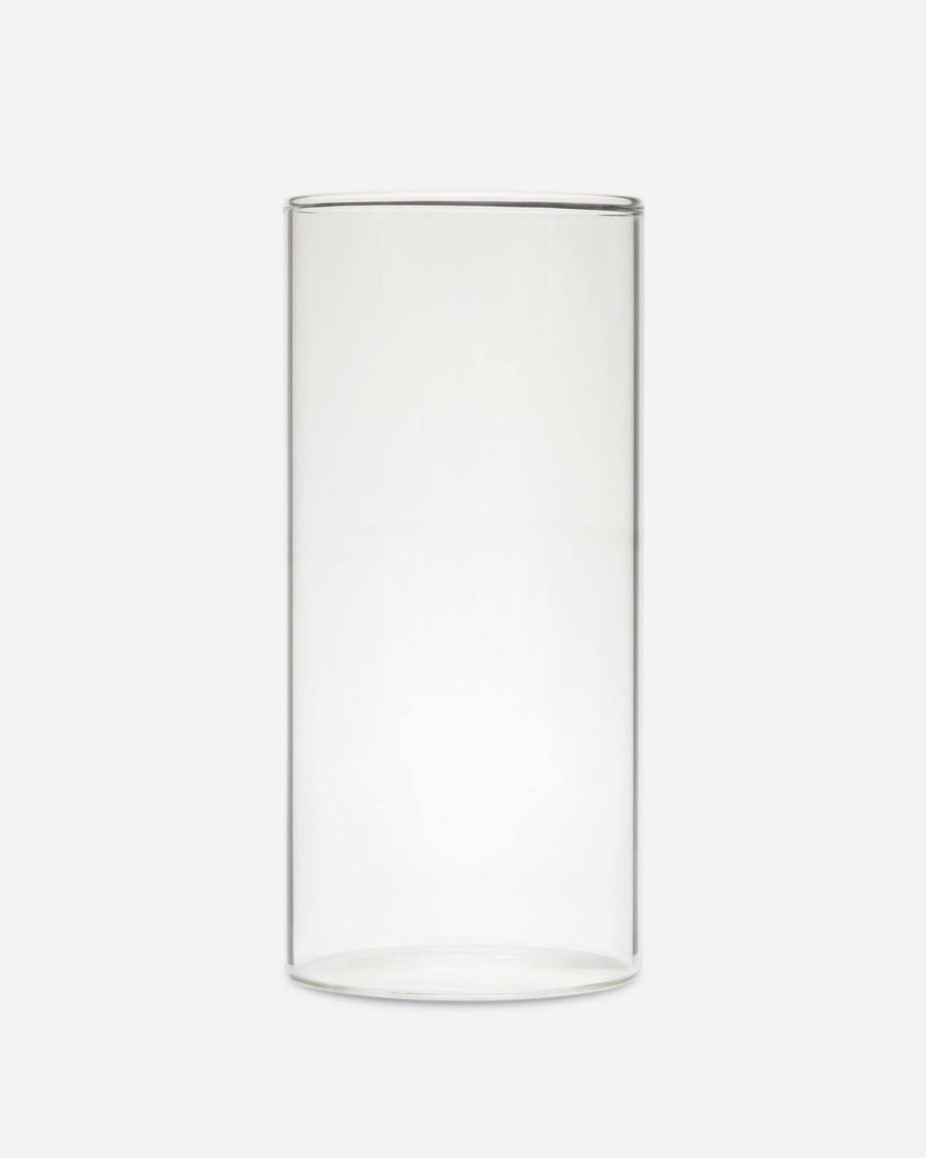 Single tall slim handblown drinking glass with straight sides shown on a pale gray background