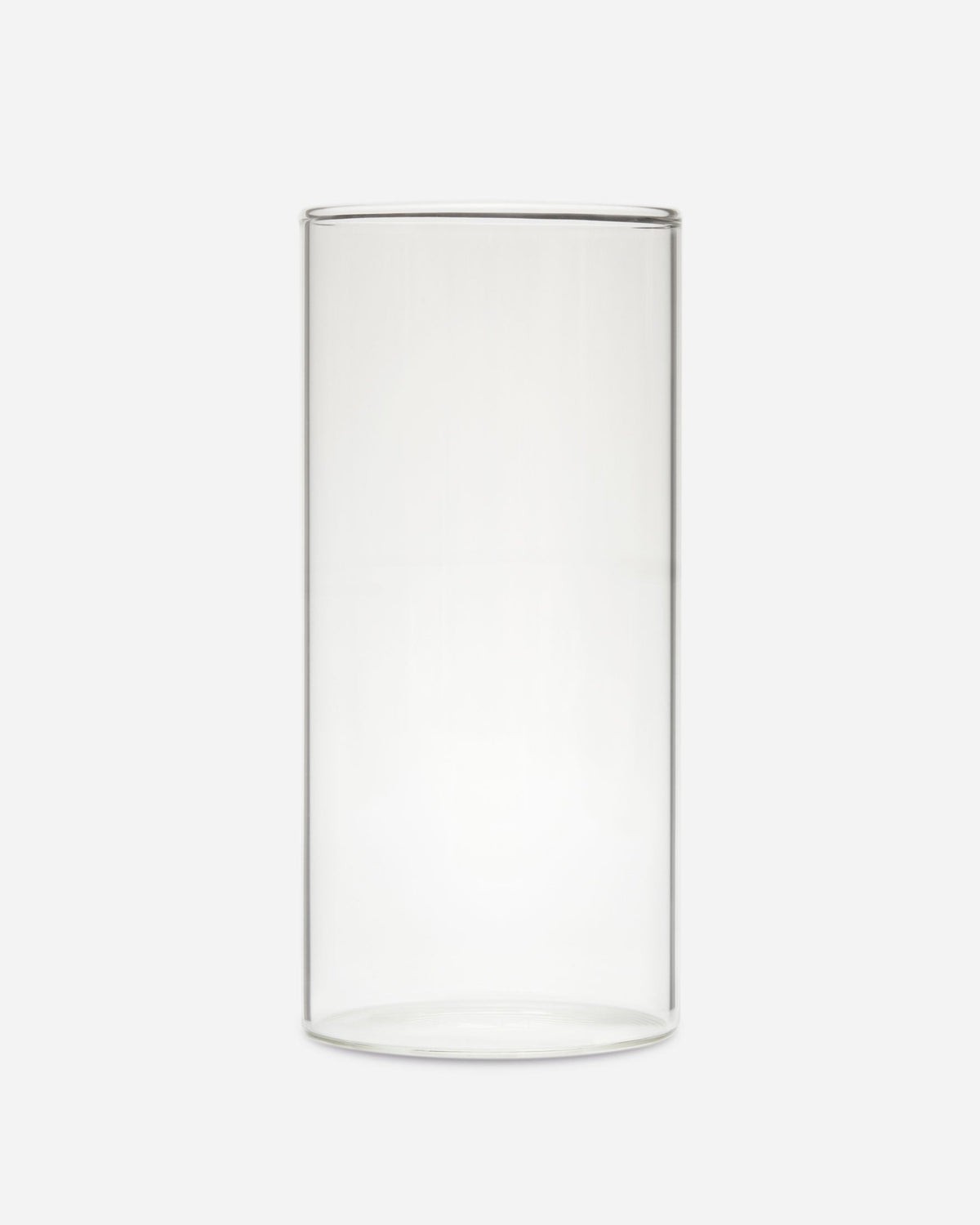 Single tall slim handblown drinking glass with straight sides shown on a pale gray background