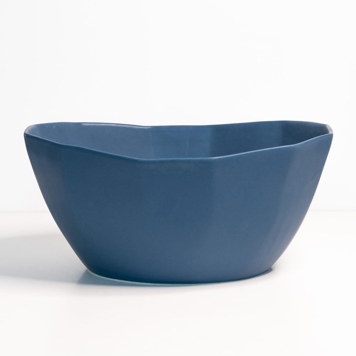 Empty large porcelain serving bowl in Pisgah Blue, a deep denim-toned glaze on a faceted oval form