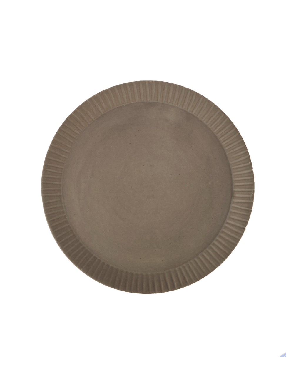 Round carved-rim ceramic platter in a warm clay-toned glaze seen from above against a dark green background