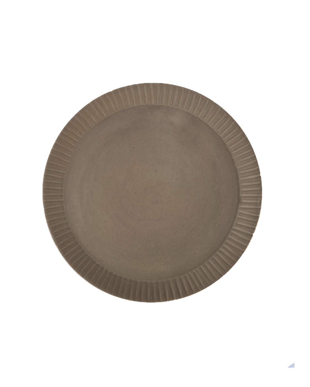Round carved-rim ceramic platter in a warm clay-toned glaze seen from above against a dark green background