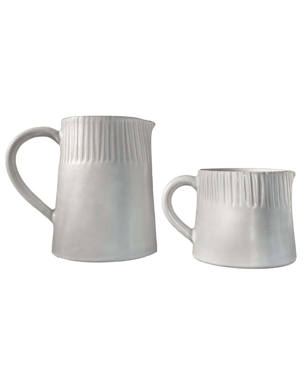 Large and small carved matte white ceramic pitchers side by side on a deep green background