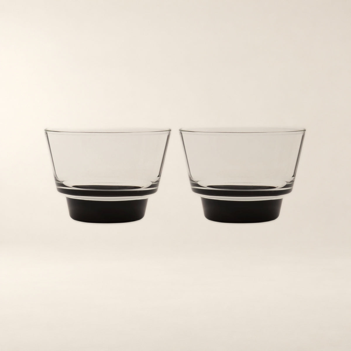 Cirrus Stackable Borosilicate Glass Cups, Black Base, Set of 2 on a warm bone background.