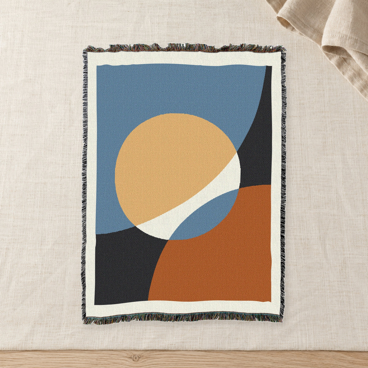 Clay Sun Abstract Woven Cotton Throw on raw linen with a folded napkin.